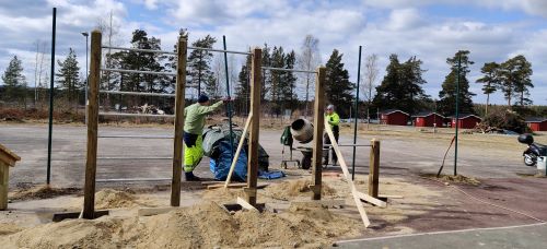 Tv personer och en cementblandare bakom utrustning som ska gjutas fast.