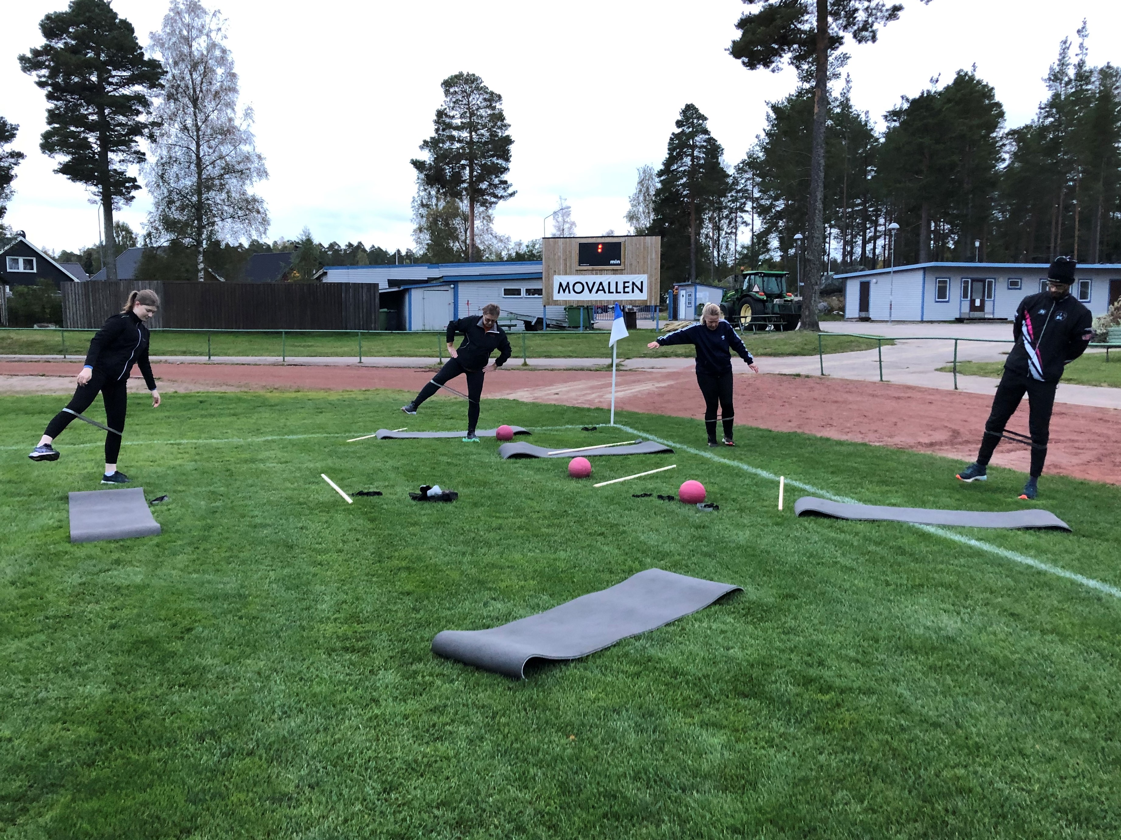 Fyra vuxna personer som trnar styrketrning p en fotbollsplan